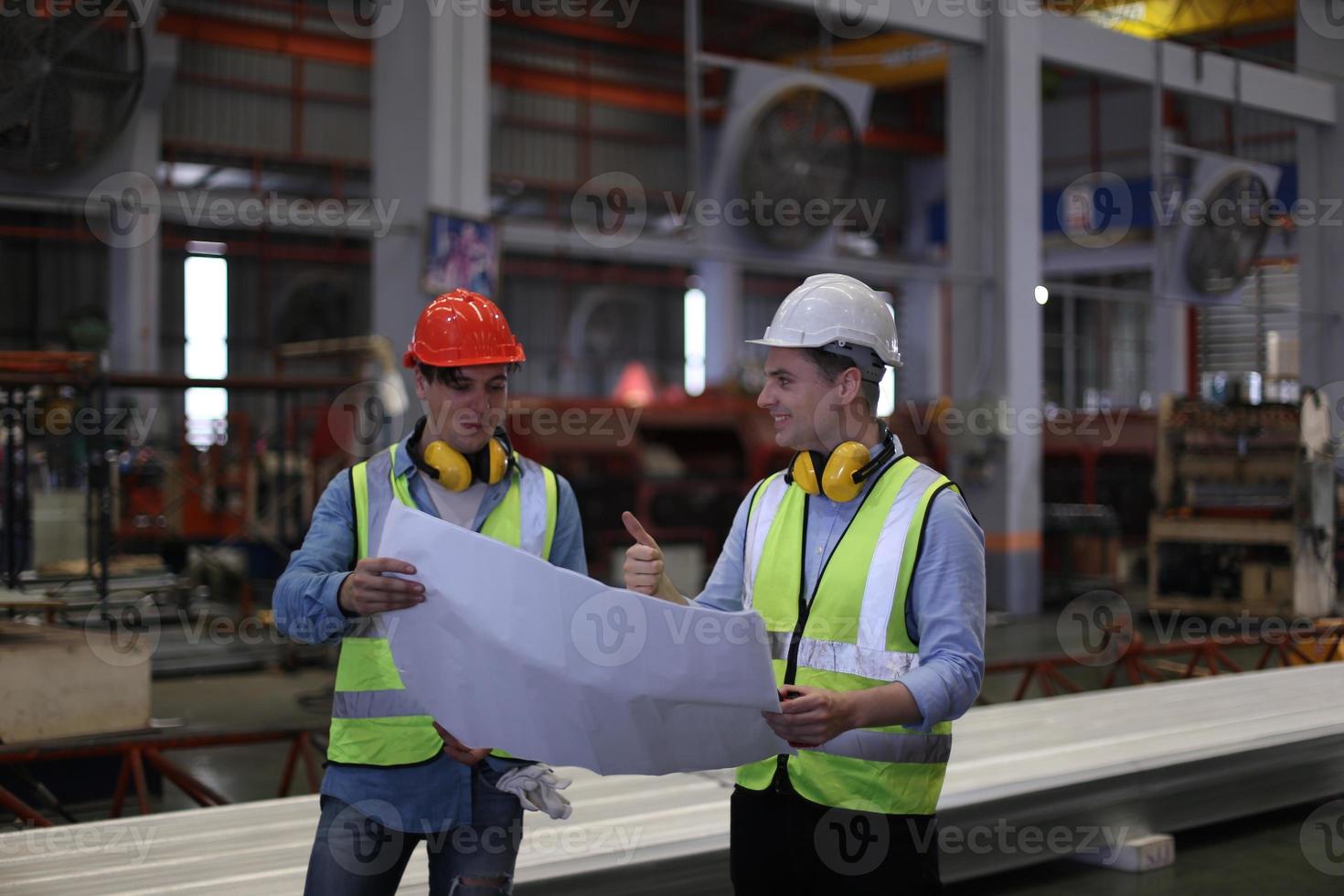 Men industrial engineer wearing a safety helmet while standing in a heavy industrial factory. The Maintenance looking of working at industrial machinery and check security system setup in factory. photo