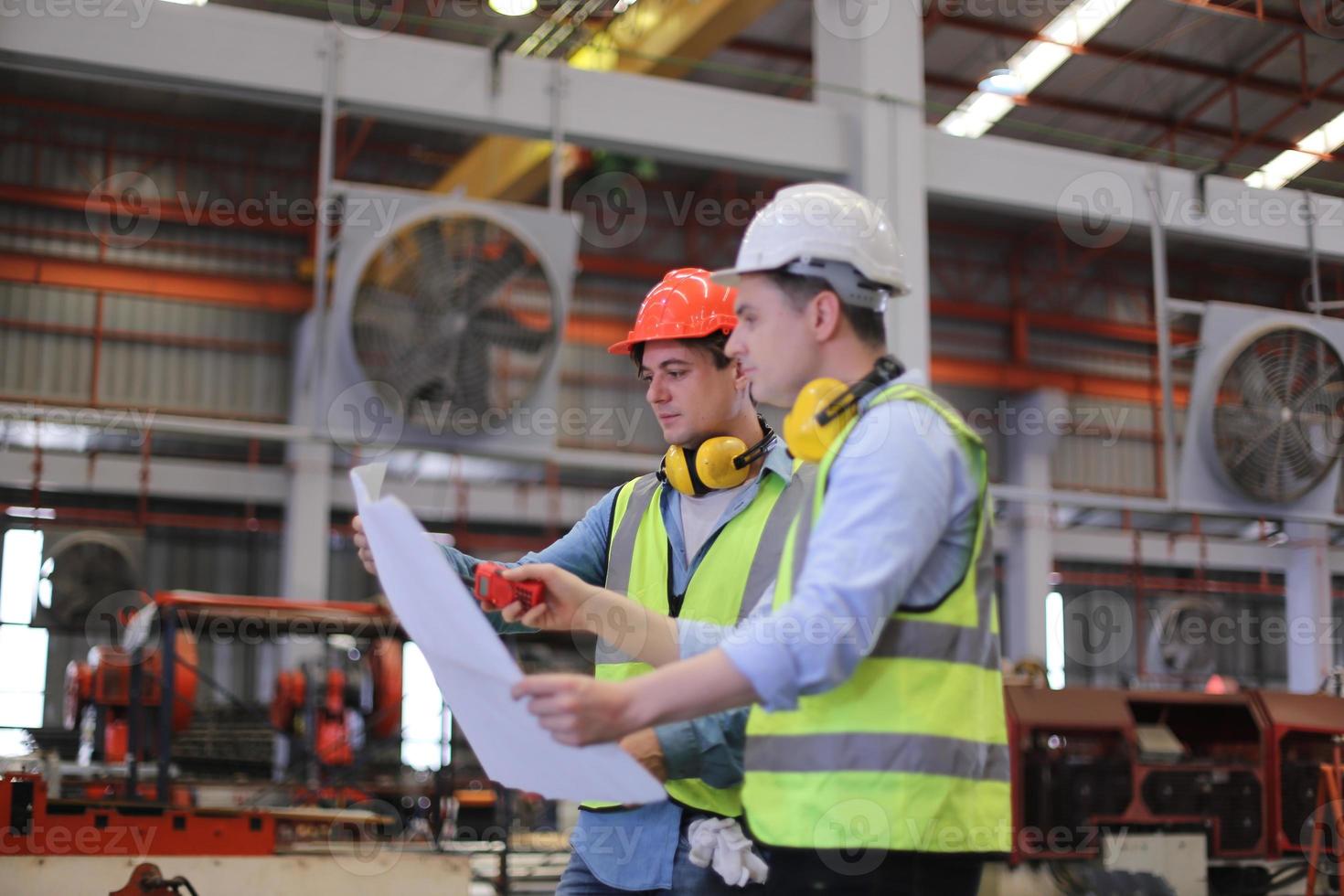 ingeniero industrial masculino con casco de seguridad mientras está de pie en una fábrica industrial pesada. el mantenimiento que busca trabajar en maquinaria industrial y verificar la configuración del sistema de seguridad en fábrica. foto