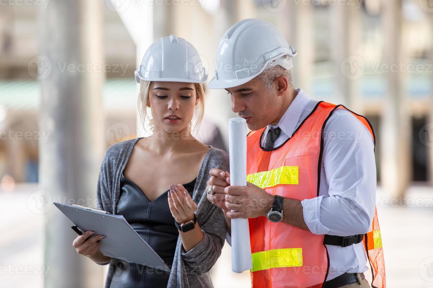 Contractor and architect looking at plan and talking about working on big project. Building in construction process interior. photo