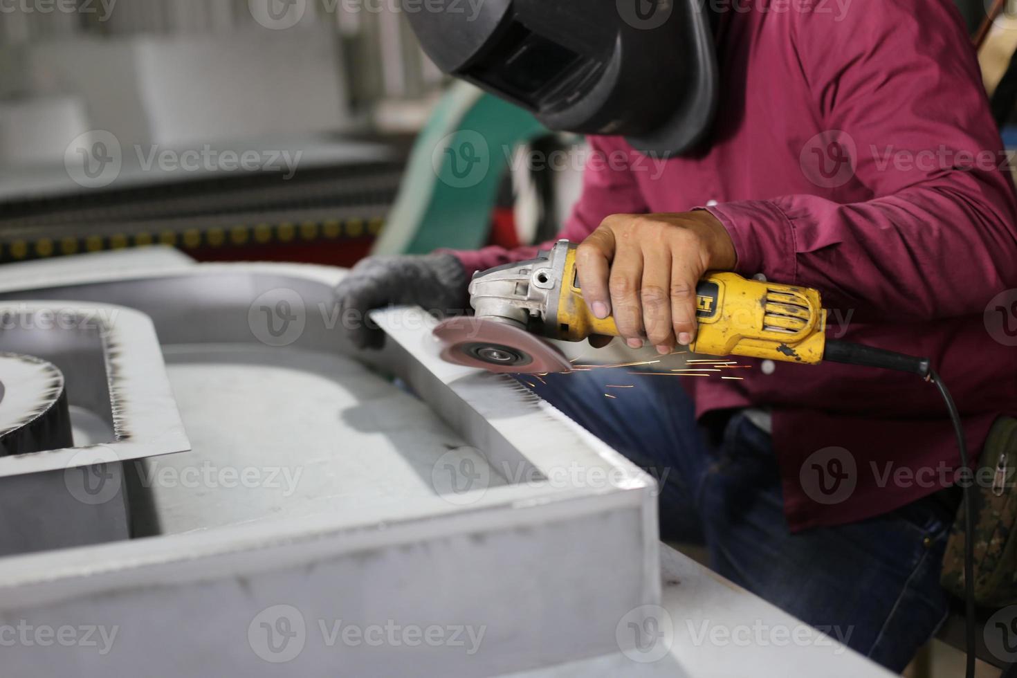 Welder used grinding stone on steel in factory with sparks, Welding process at the industrial workshop, hands with instrument in frame. photo