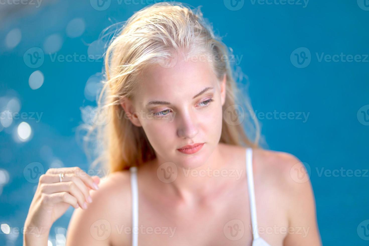 mujer en bikini blanco bronceándose junto a la piscina foto