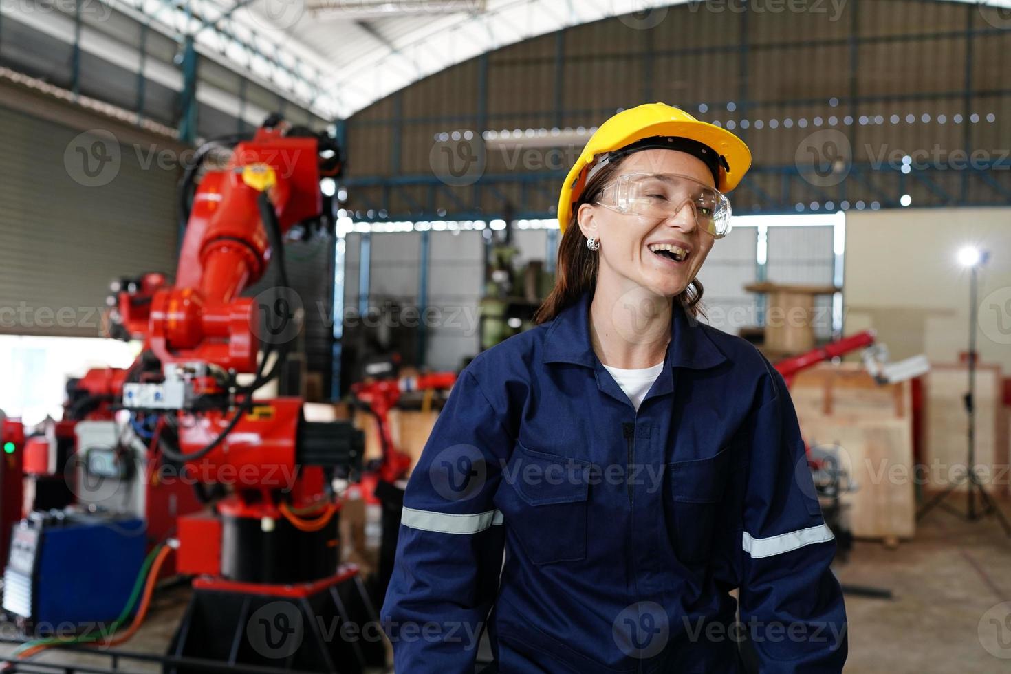 Professional young industrial factory woman employee working with machine part, checking and testing industrial equipment and robot arms in large Electric electronics wire and manufacturing plant photo
