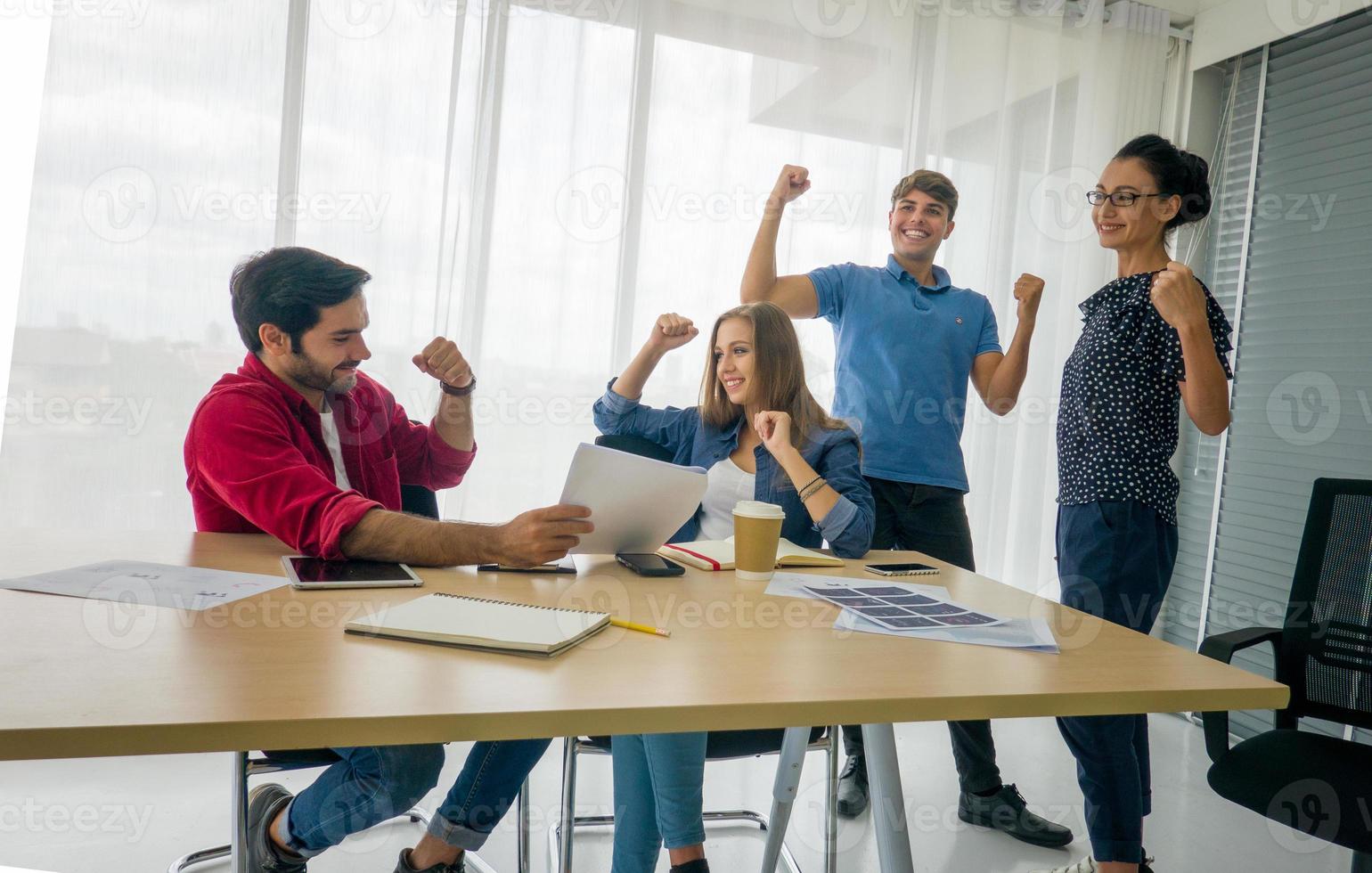 grupo diverso de jóvenes empresarios discutiendo un proyecto de trabajo mientras se sientan juntos en una mesa en una oficina moderna. concepto de coworking foto