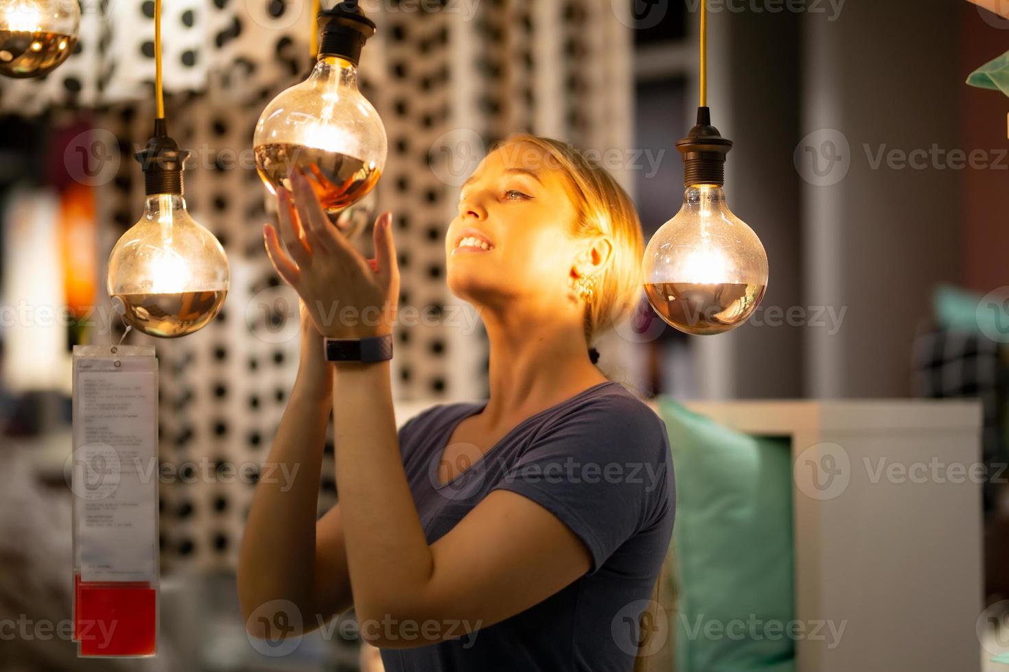 women holding and looking at bulb light reflected on her face photo