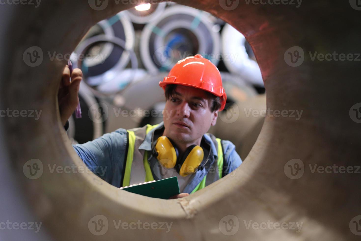 Men industrial engineer wearing a safety helmet while standing in a heavy industrial factory. The Maintenance looking of working at industrial machinery and check security system setup in factory. photo