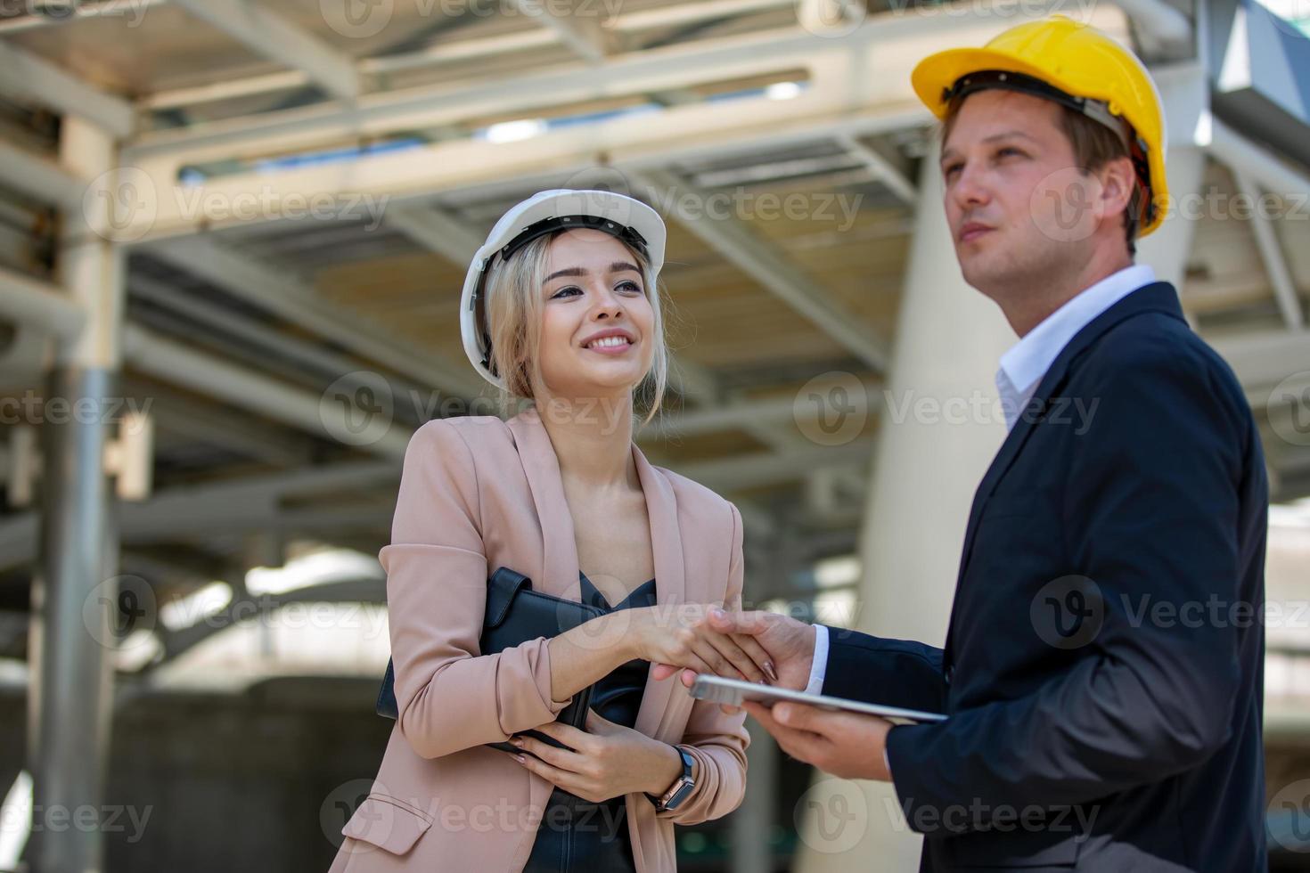 el ingeniero y la mujer de negocios revisando el portapapeles en el edificio del sitio de construcción. el concepto de ingeniería, construcción, vida urbana y futuro. foto