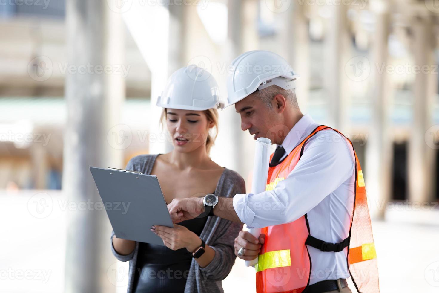 Contractor and architect looking at plan and talking about working on big project. Building in construction process interior. photo