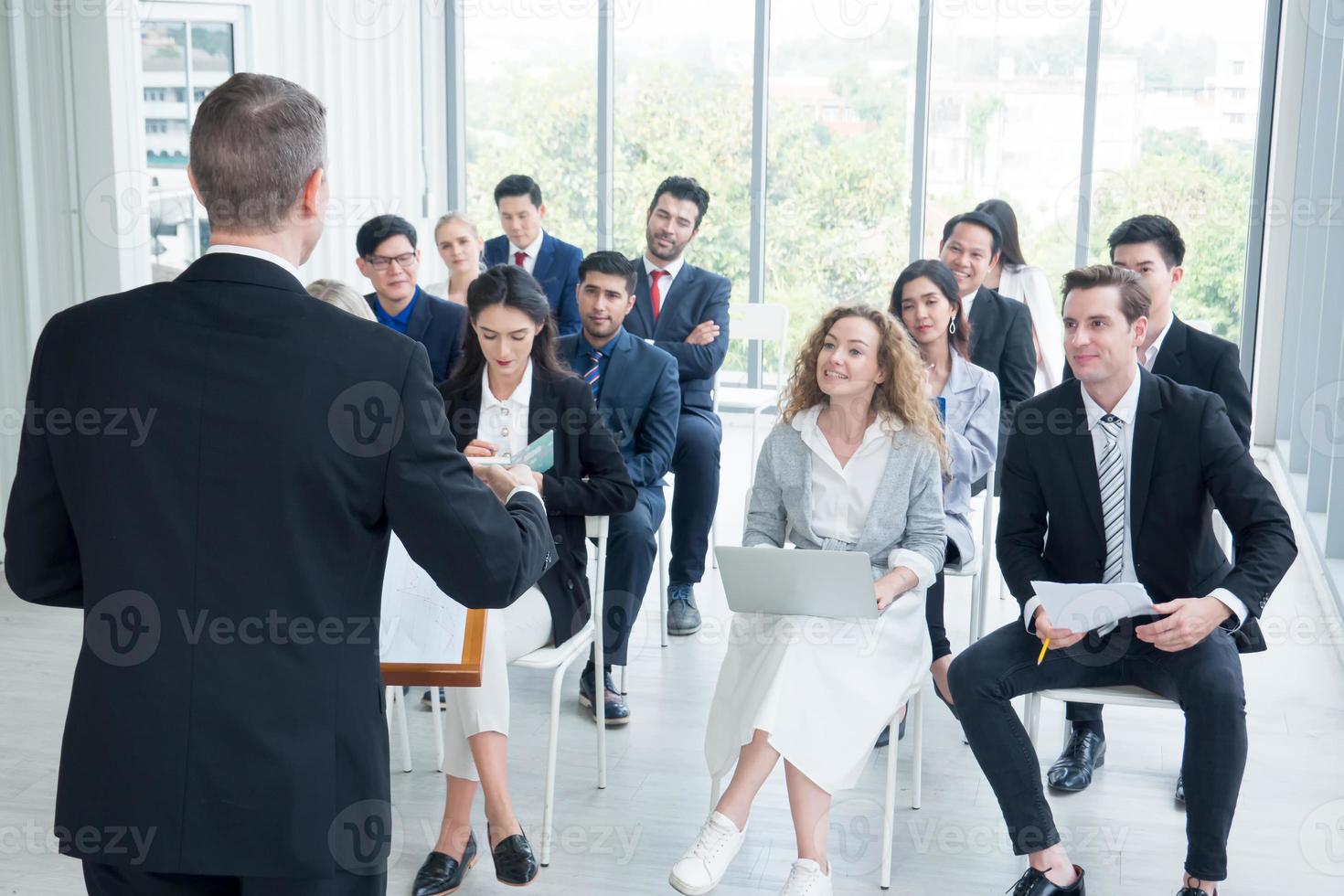 Speaker giving presentation in hall. Audience or conference hall. Rear view of unrecognized participants in audience. Scientific conference event, training photo