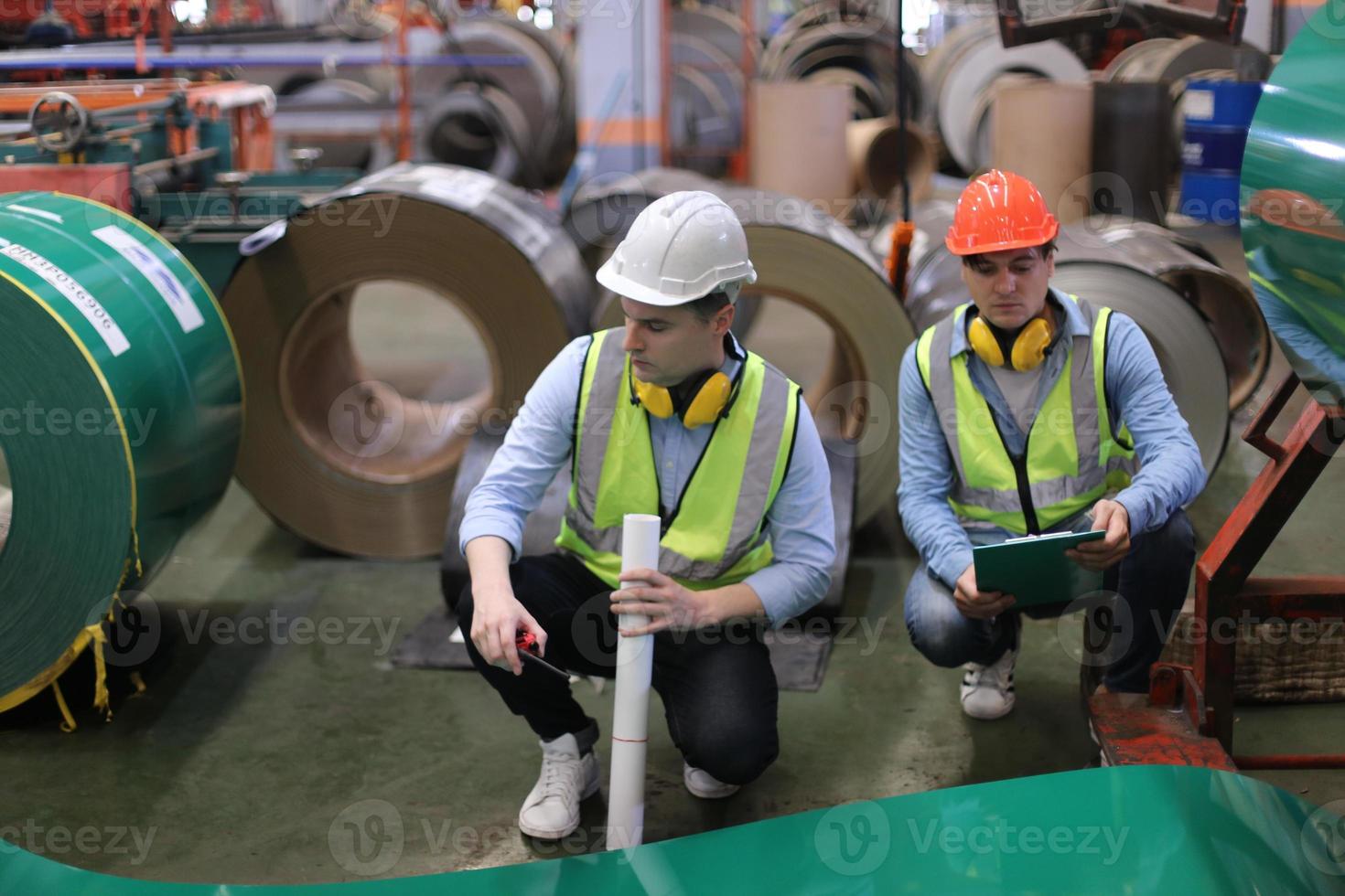 el capataz de los trabajadores de la industria o el trabajo de los trabajadores en el sitio de la fábrica revisan la máquina o los productos en el sitio. ingeniero o técnico revisando material o máquina en planta. industrial y fábrica. foto