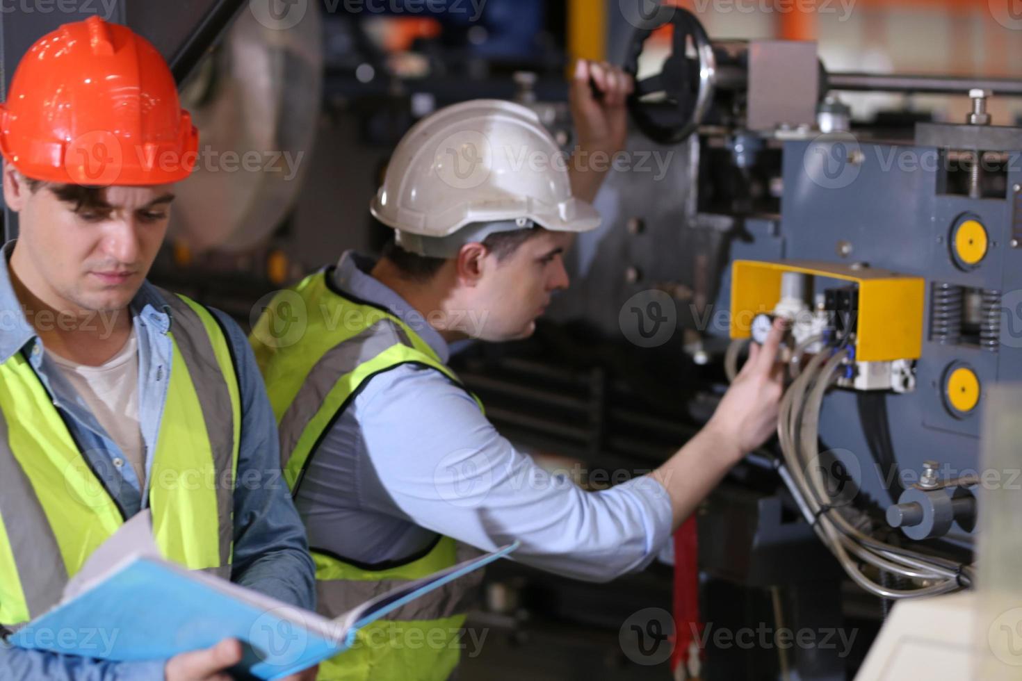 Men industrial engineer wearing a safety helmet while standing in a heavy industrial factory. The Maintenance looking of working at industrial machinery and check security system setup in factory. photo