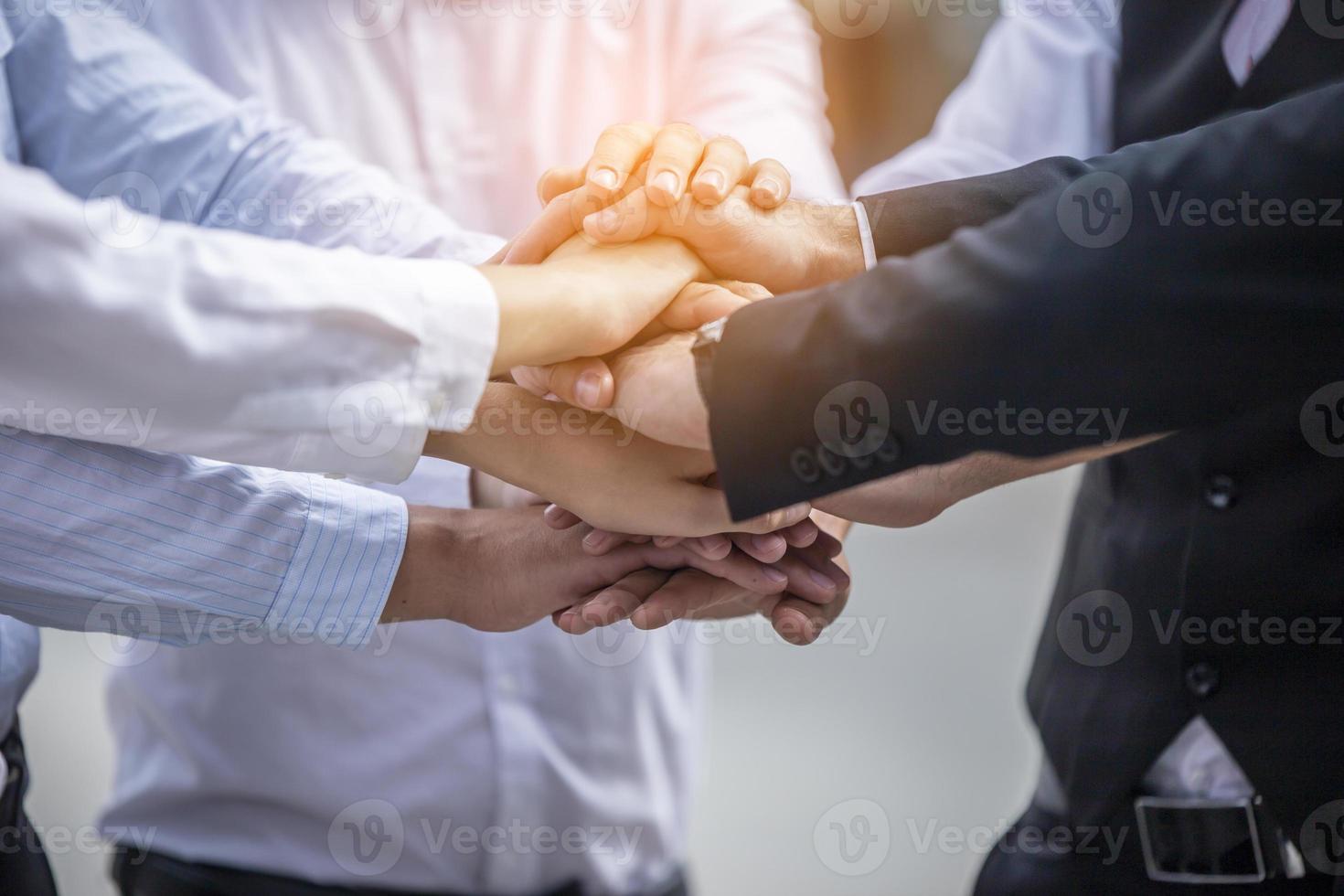 Stack of hands. Unity and teamwork concept. Close up top view of young business people putting their hands together photo