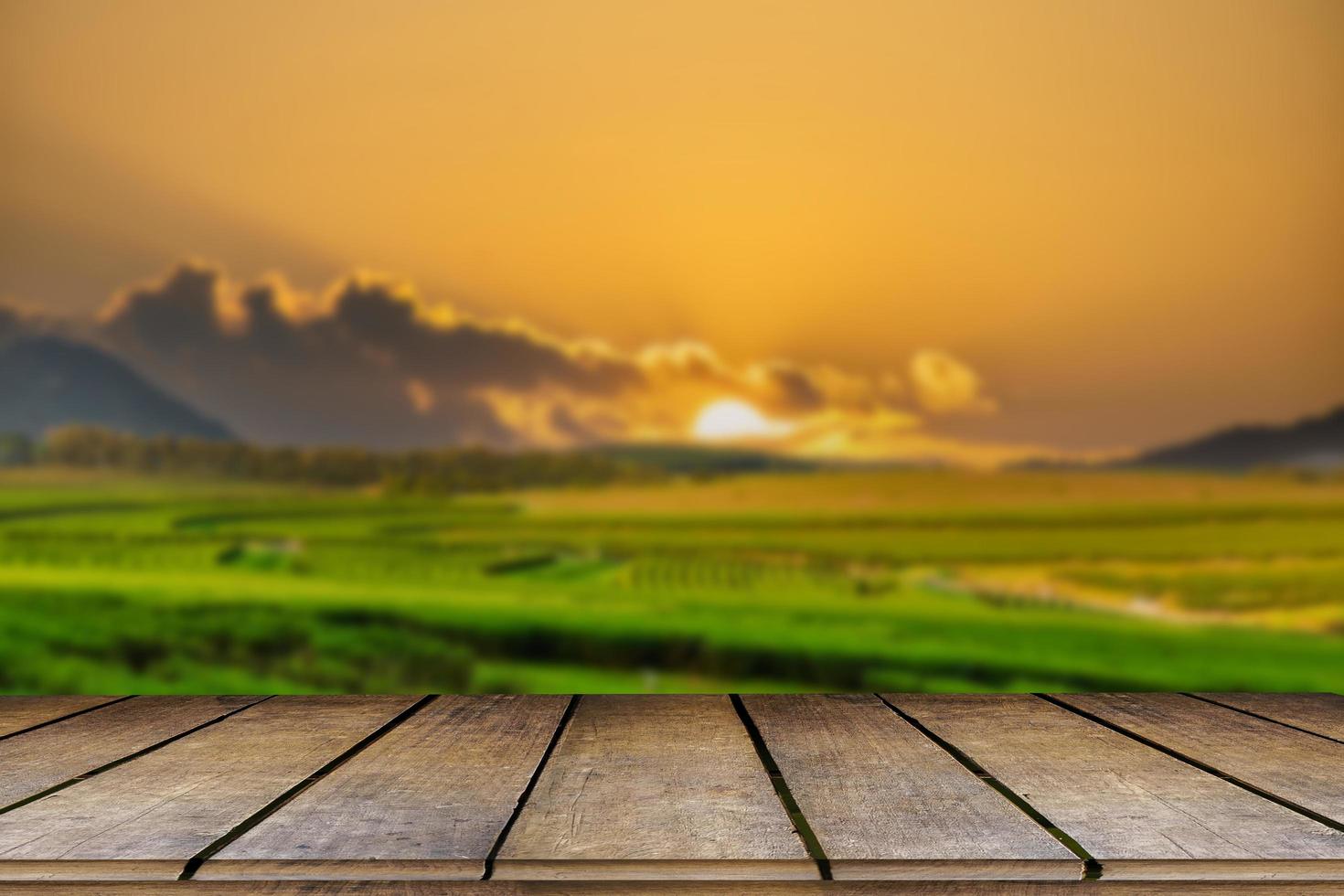 Wooden floor with beautiful sunset blur image of tea plantation background. photo