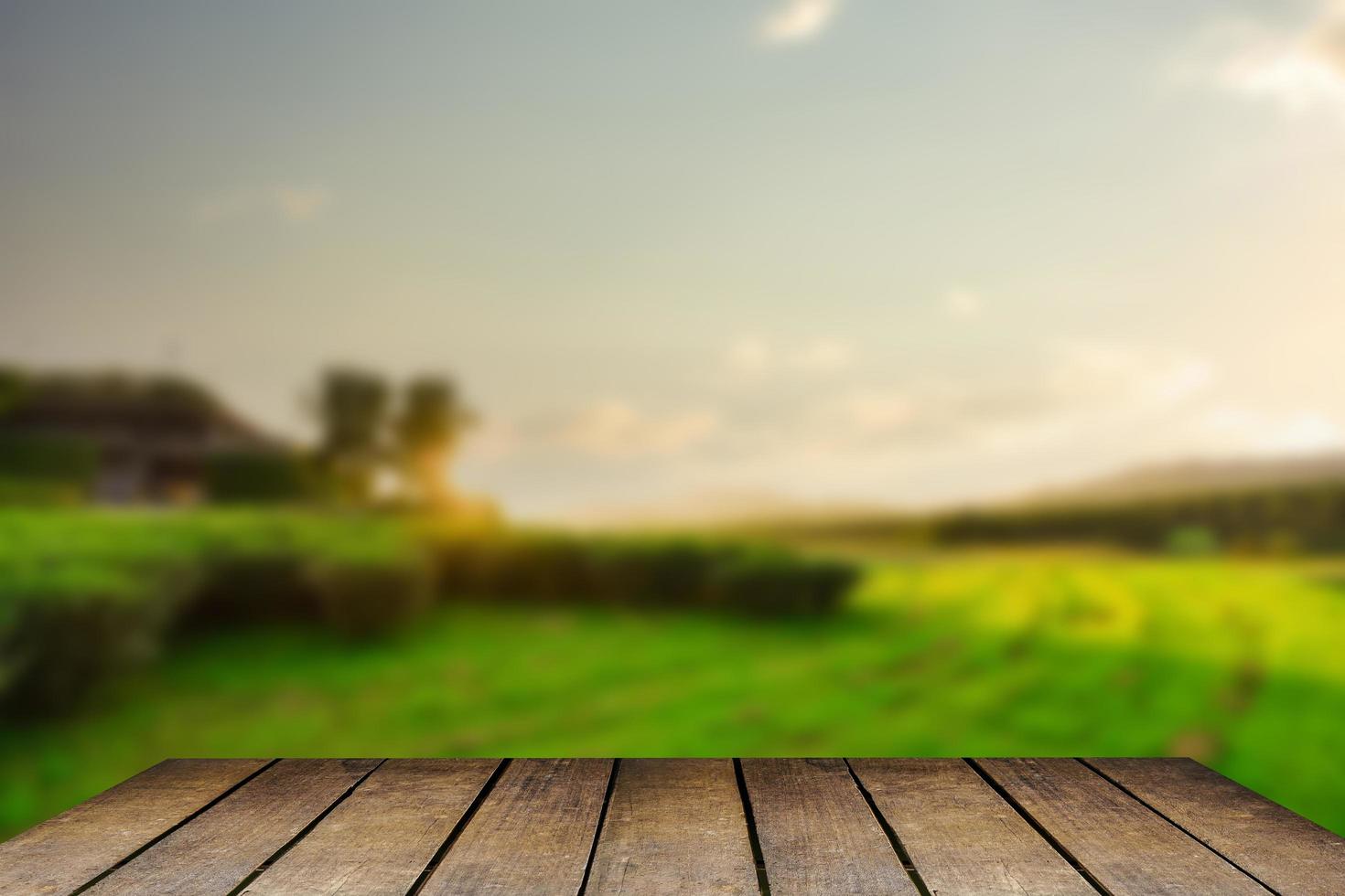 Wooden floor with beautiful sunset blur image of tea plantation background. photo