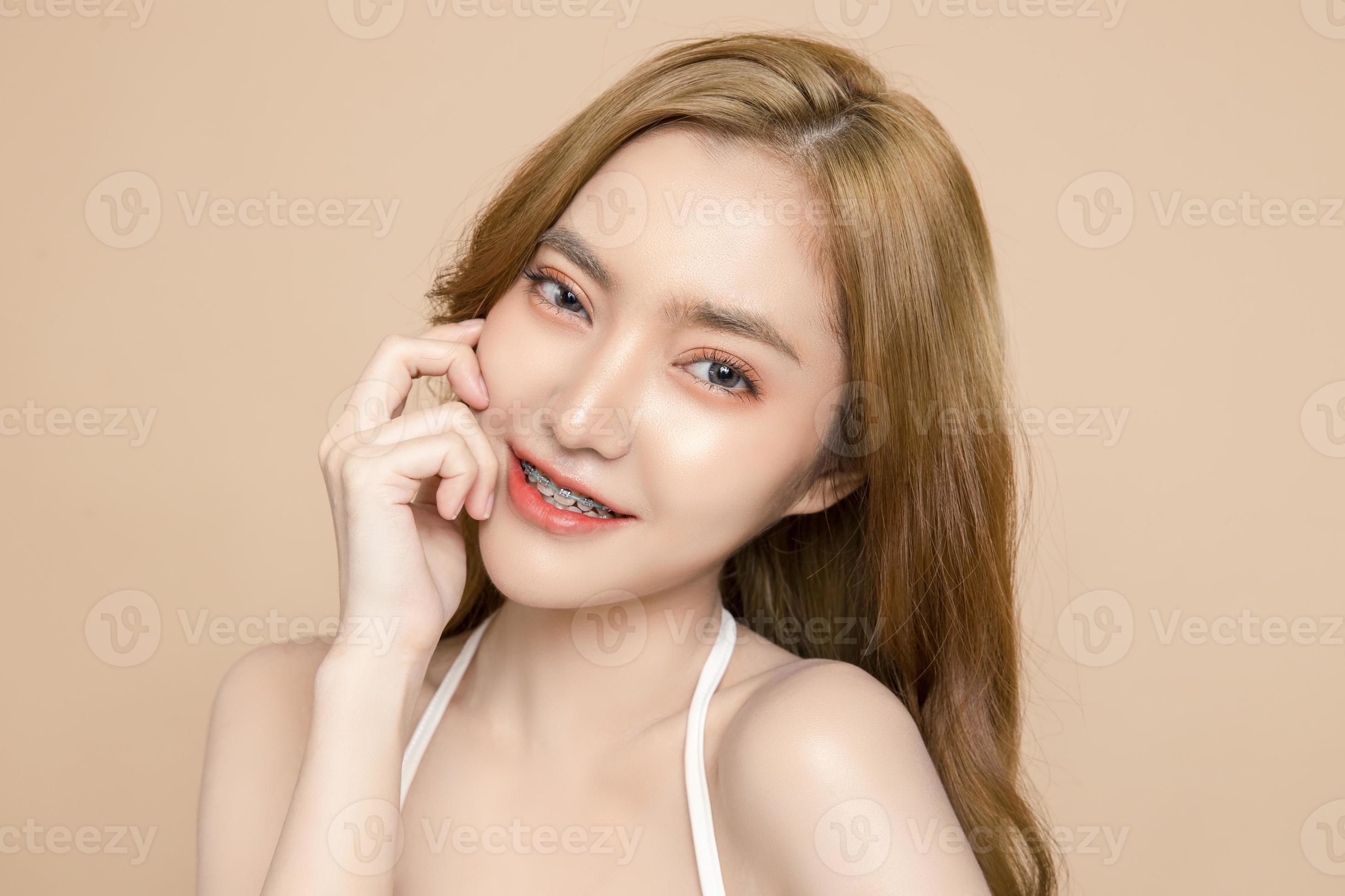 Cute young Asian woman wearing braces is feeling happy with clean fresh  skin isolated over cream background. Plastic surgery Face care, Facial  treatment, Cosmetology, beauty and spa, Women portrait. 7073962 Stock Photo