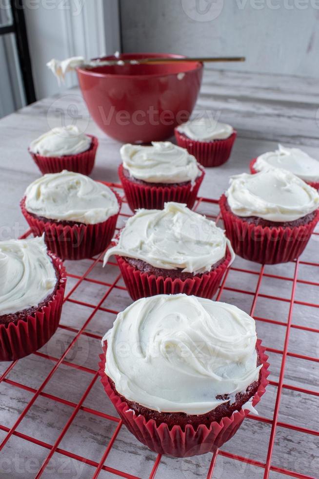 red velvet cupcakes with white icing on red wire rack photo