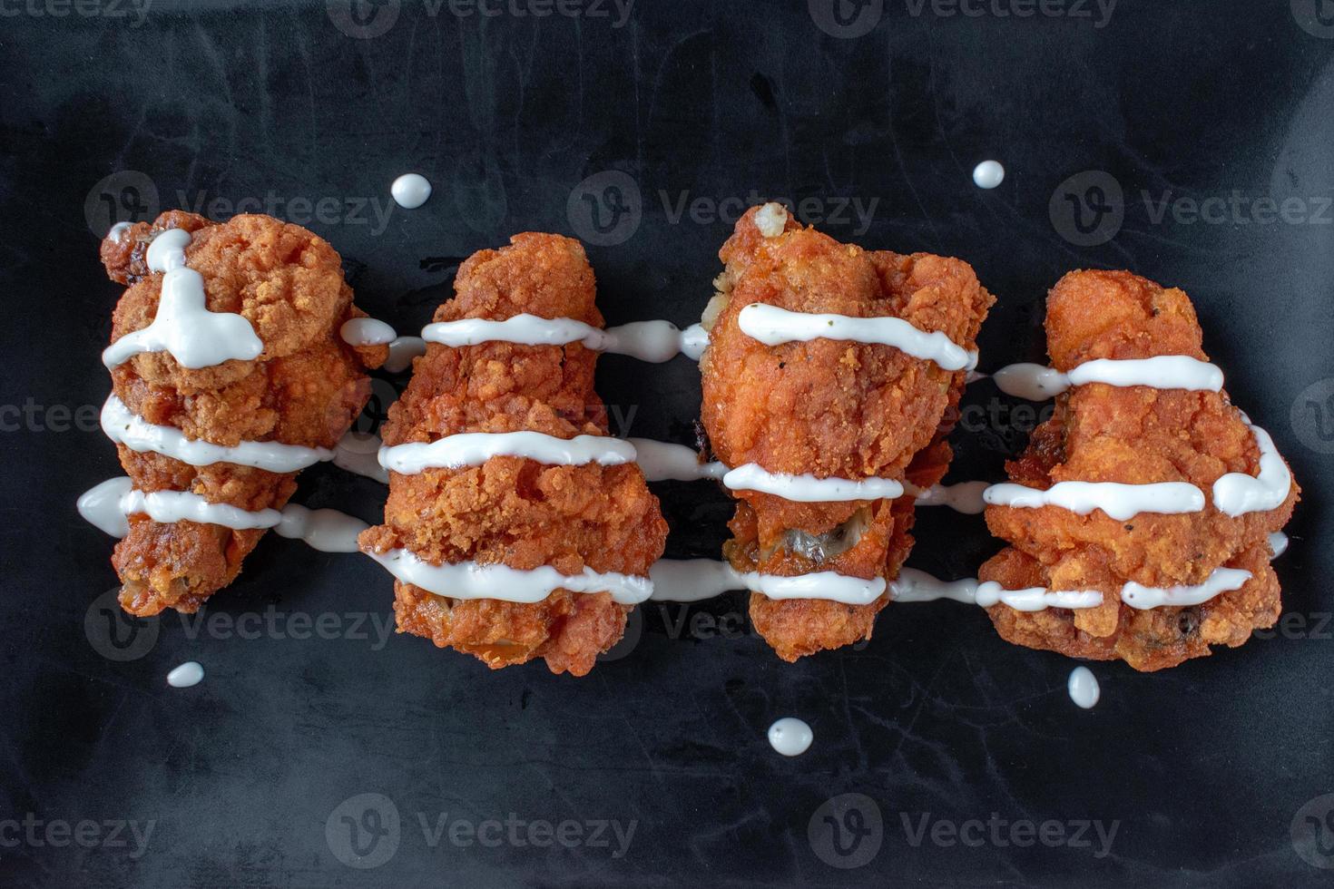 chicken wings with drizzle of white sauce top down on dark background photo