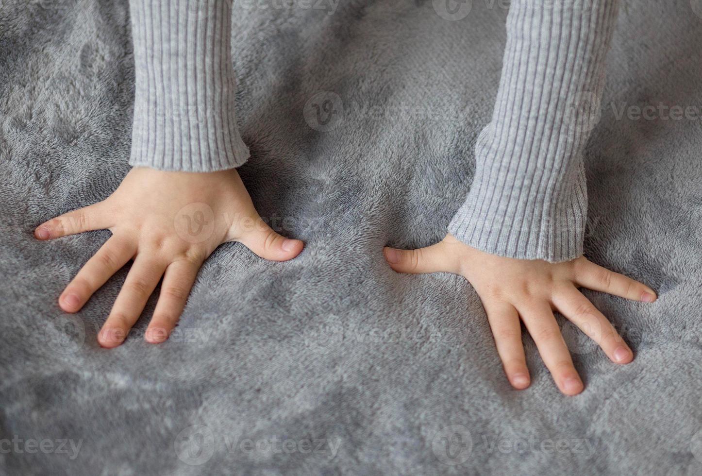 Two children's hands with fingers apart rest on the surface photo