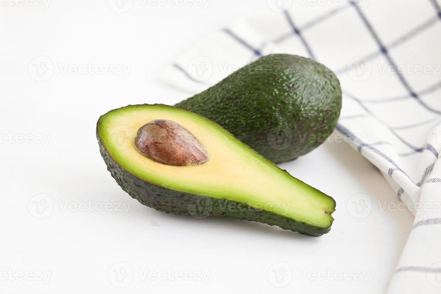 Whole and cut avocados on the table with napkin Close-up photo