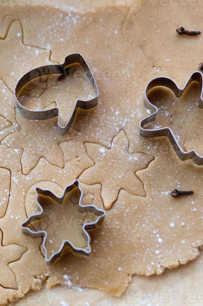 masa de jengibre enrollada sobre la mesa con cortadores de galletas de navidad. siluetas en la prueba. galletas navideñas vistas desde arriba foto