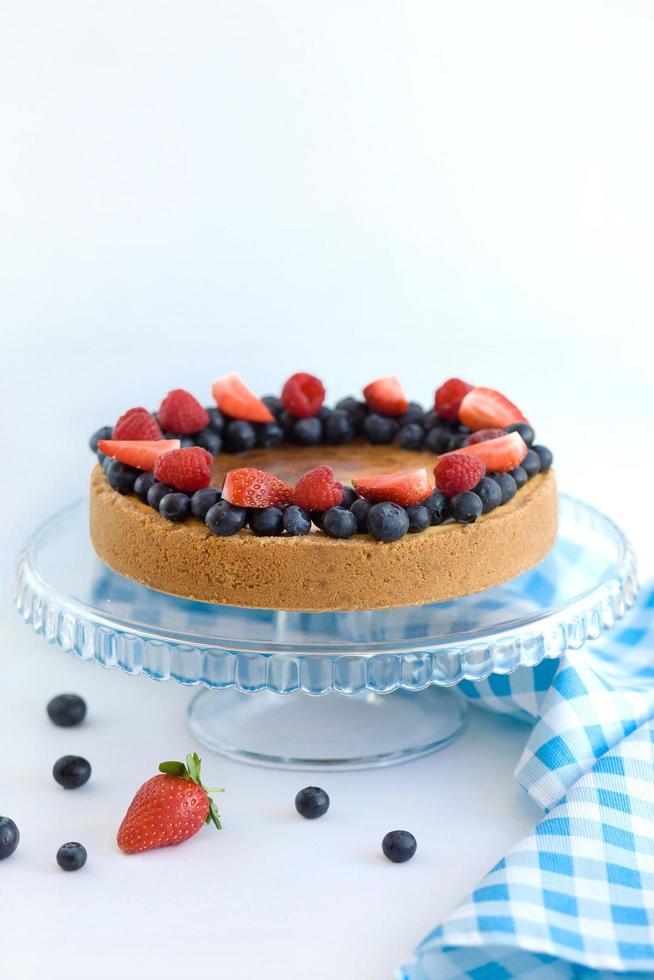 Cheesecake with berries on a glass stand on a light background with a blue napkin photo