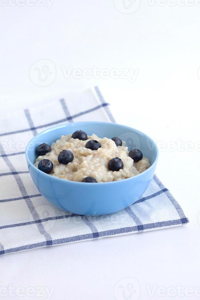 Oatmeal porridge with blueberries in a blue plate on a checkered napkin. Food photography photo