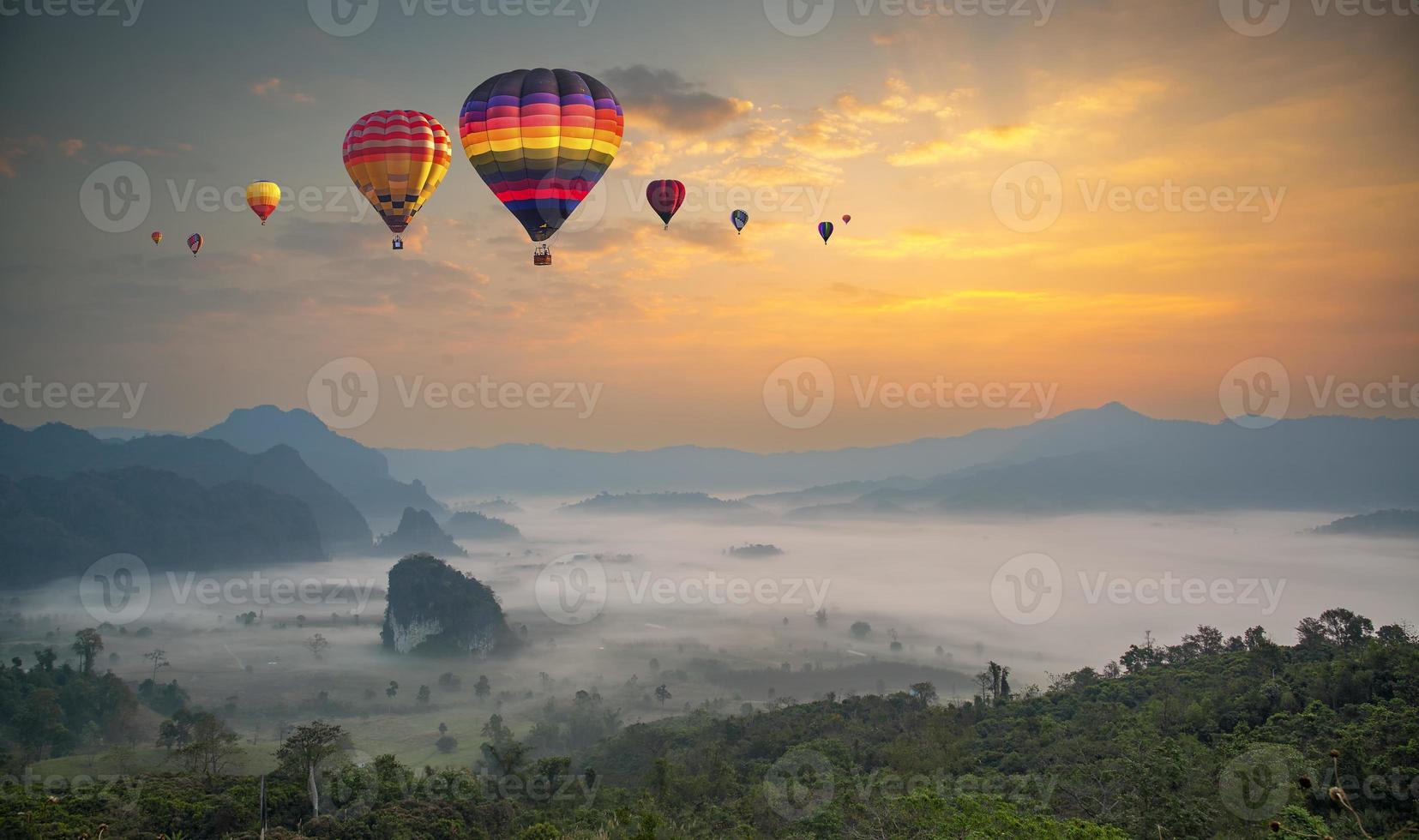 coloridos globos aerostáticos volando sobre la montaña y el mar de niebla al amanecer. montaña con globos aerostáticos en la mañana. foto