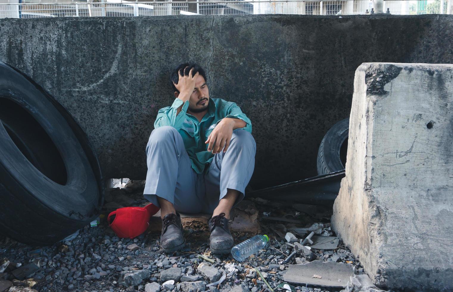 Homeless man sitting sadly beside the wall photo