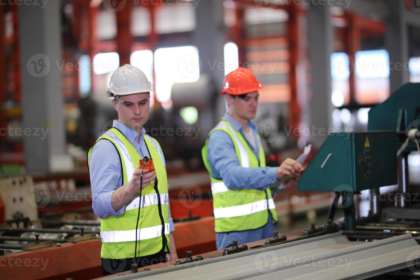 Men industrial engineer wearing a safety helmet while standing in a heavy industrial factory. The Maintenance looking of working at industrial machinery and check security system setup in factory. photo