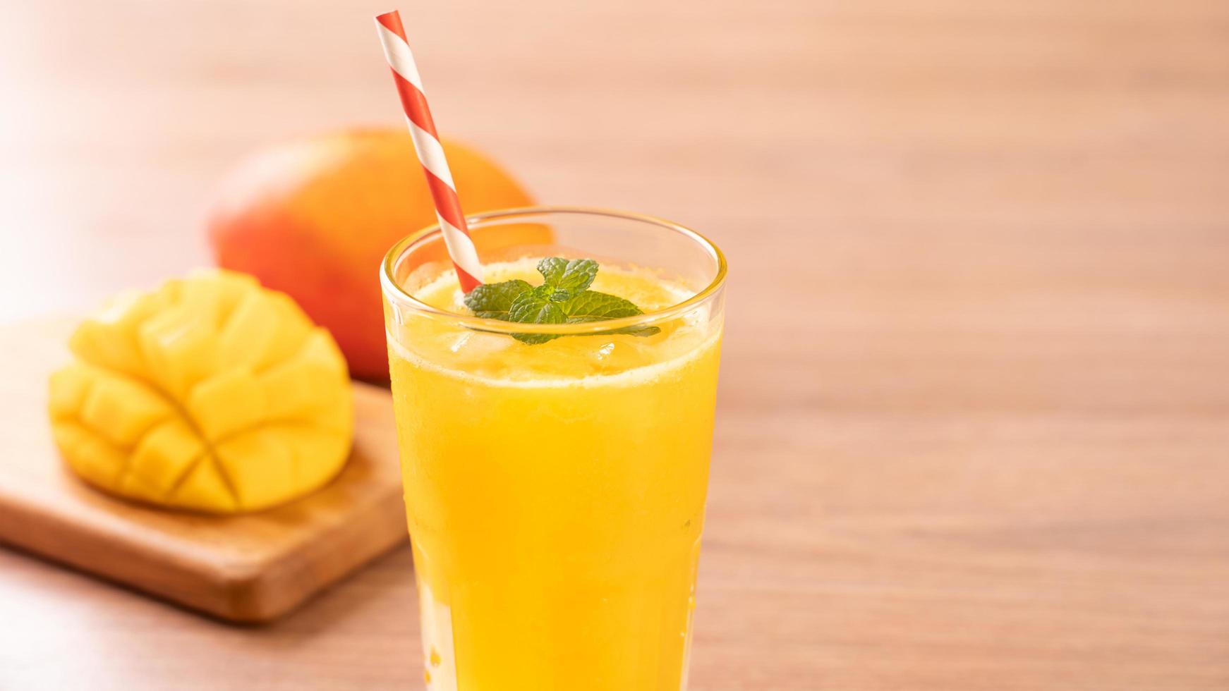 Fresh mango juice with beautiful chopped pulp flesh on bright wooden table background. Tropical fruit drink design concept. Close up, copy space. photo