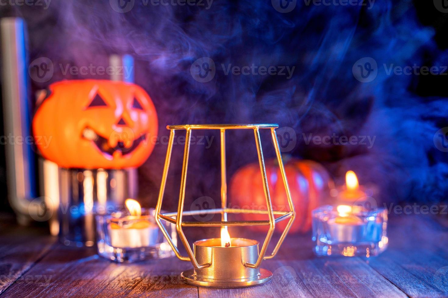 concepto de halloween, linterna de calabaza naranja y velas en una mesa de madera oscura con humo azul-naranja alrededor del fondo, truco o trato, cerrar foto