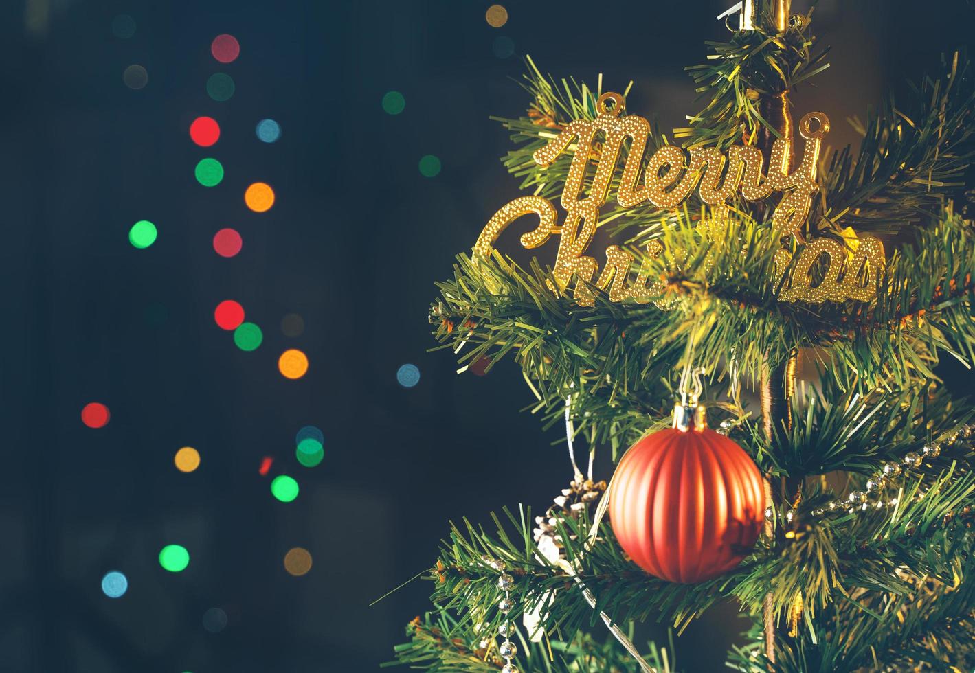 Beautiful Christmas decor concept, bauble hanging on the Christmas tree with sparkling light spot, blurry dark black background, macro detail, close up. photo