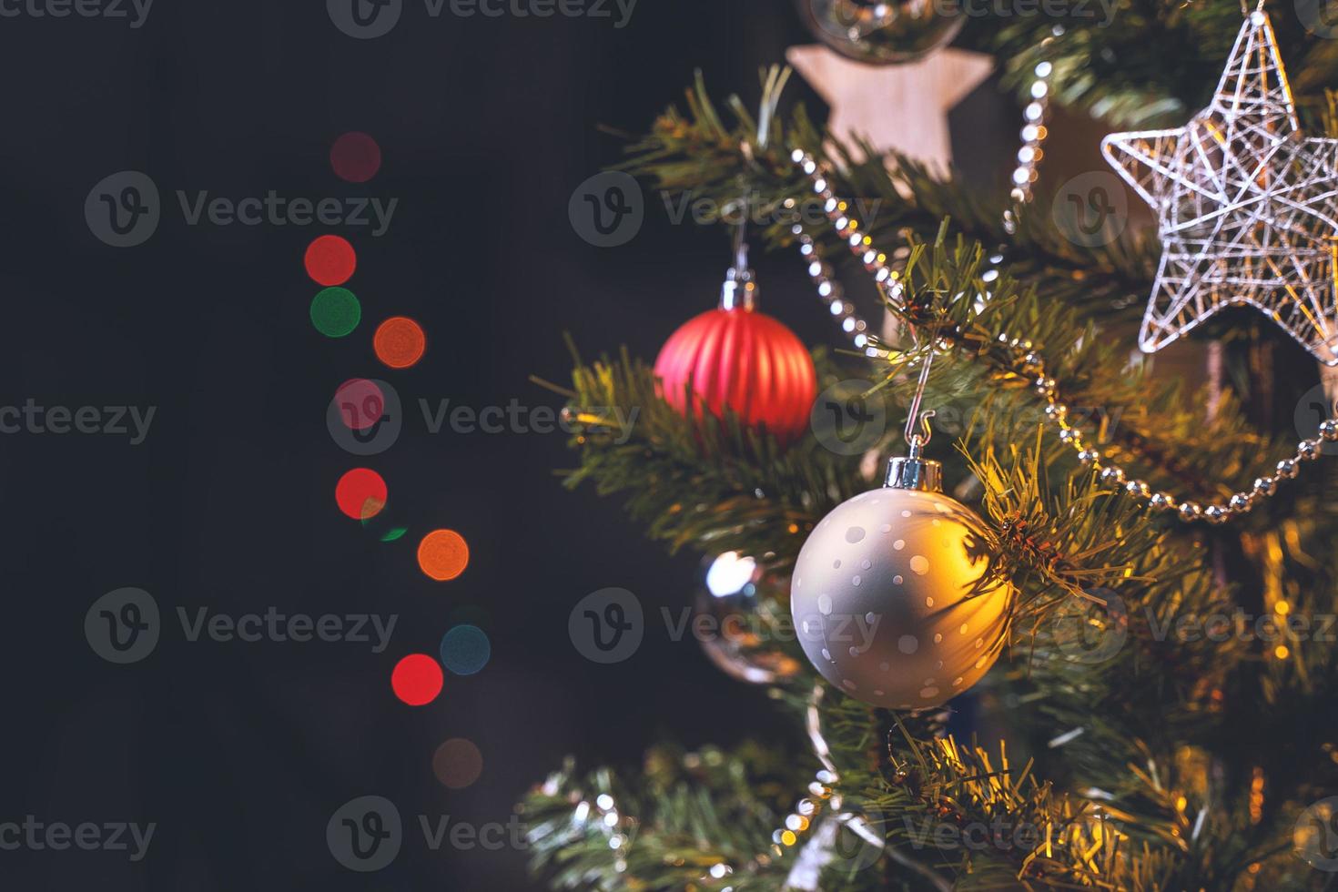 Beautiful Christmas decor concept, bauble hanging on the Christmas tree with sparkling light spot, blurry dark black background, macro detail, close up. photo