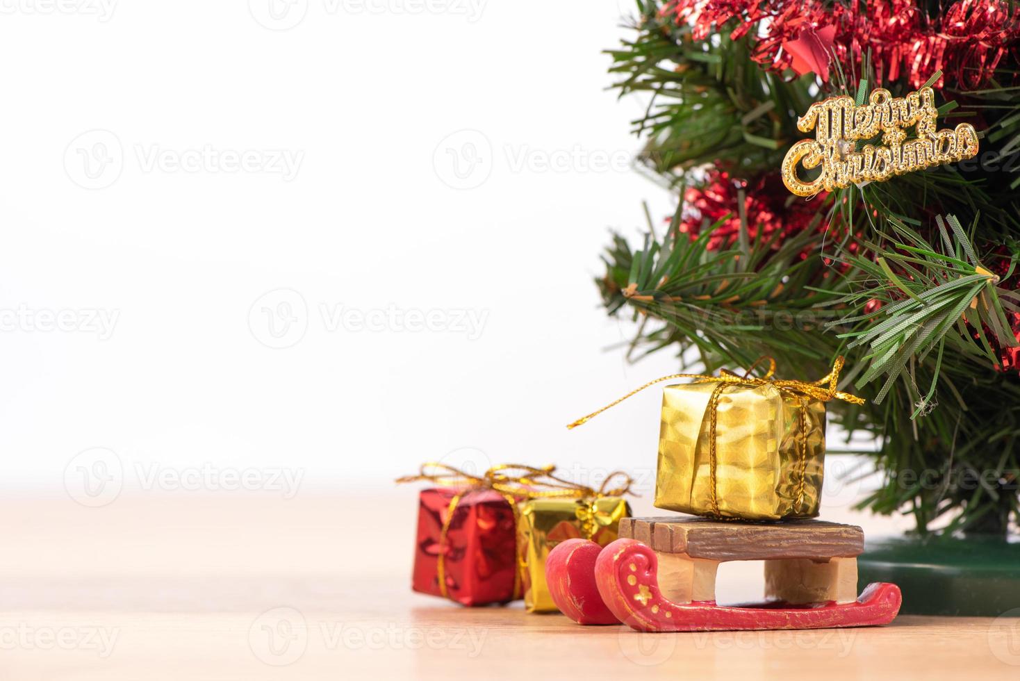 Decorated cute Christmas tree on a wooden floor with white background and toys, blank for festive design concept, close up. photo