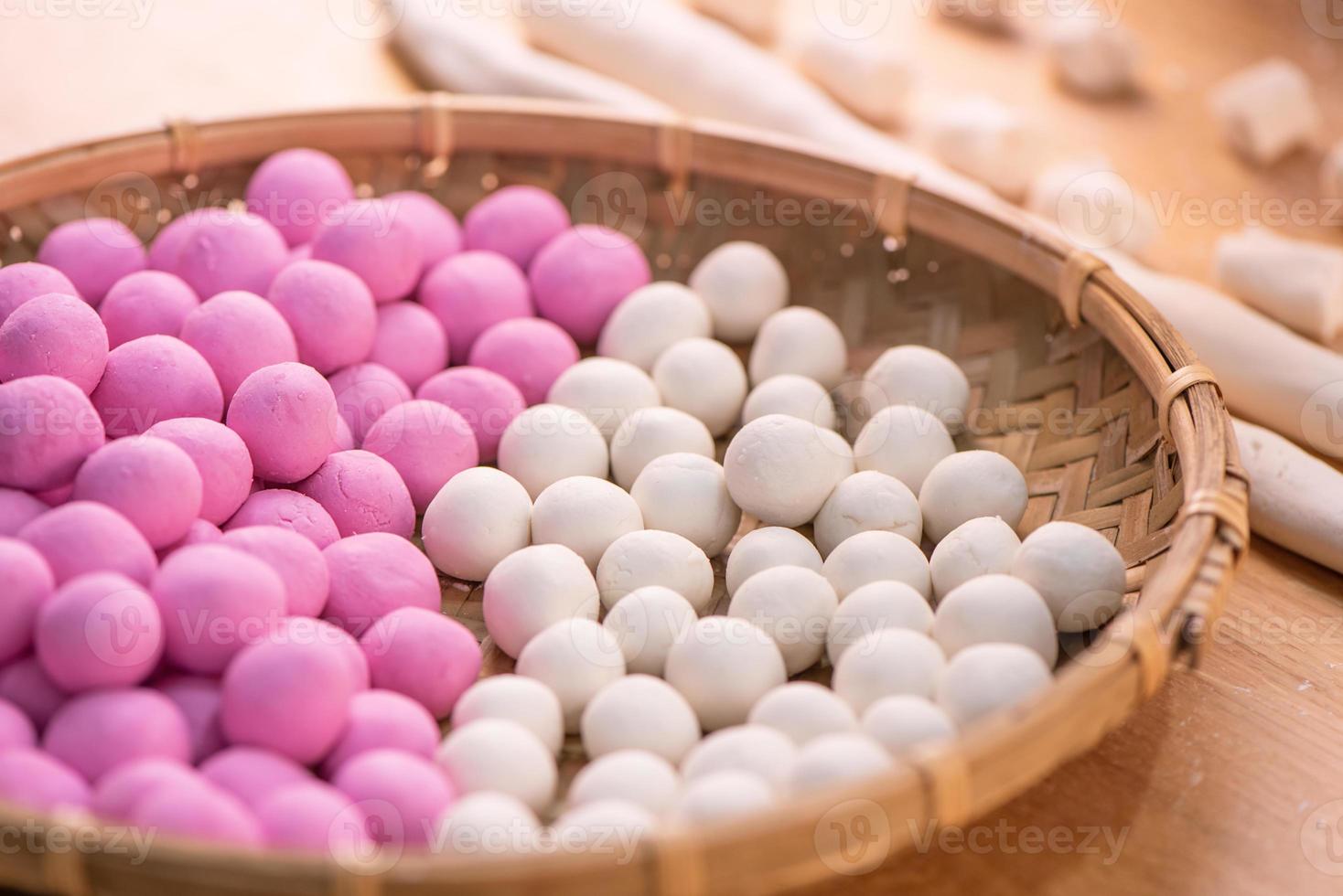 An Asia woman is making Tang yuan, yuan xiao, Chinese traditional food rice dumplings in red and white for lunar new year, winter festival, close up. photo