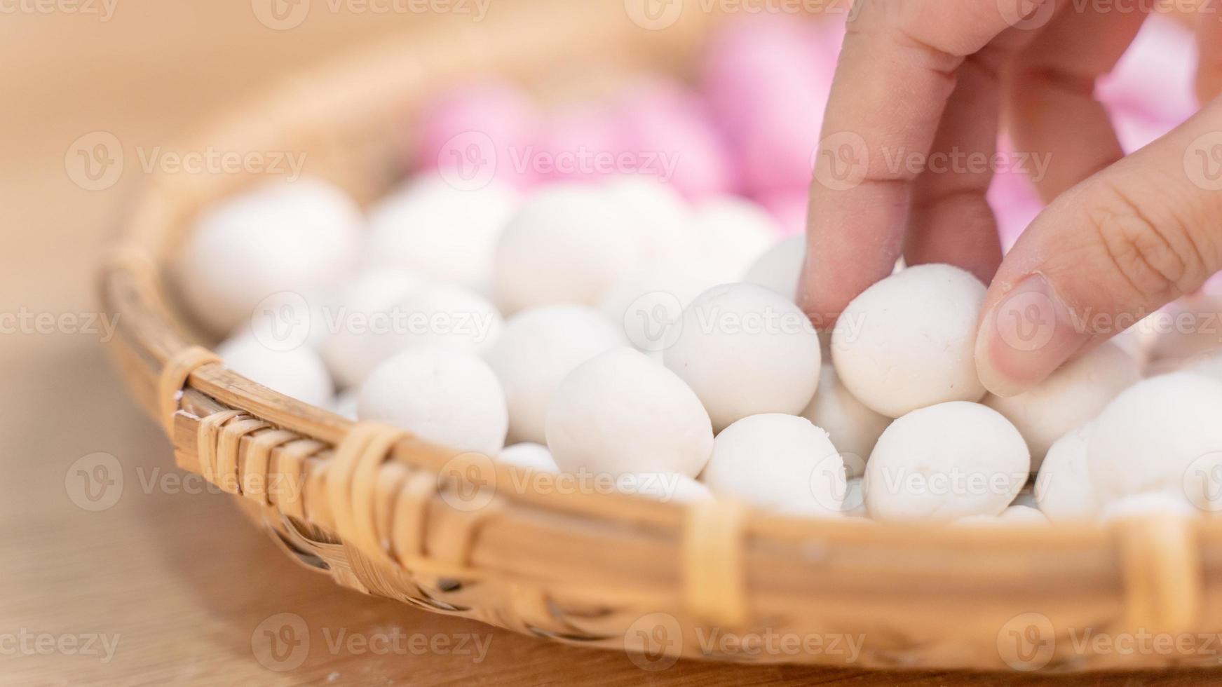 una mujer de asia está haciendo tang yuan, yuan xiao, albóndigas de arroz de comida tradicional china en rojo y blanco para el año nuevo lunar, festival de invierno, de cerca. foto