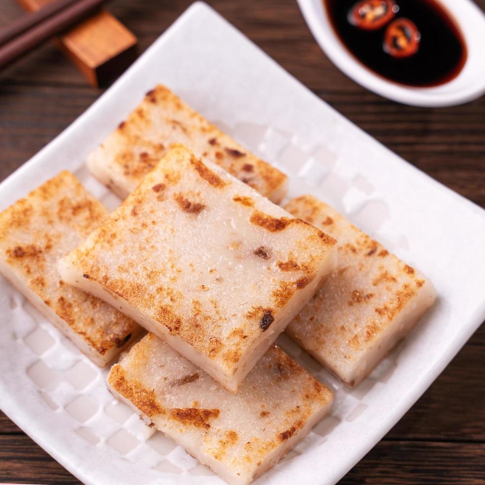 delicioso pastel de nabo, pastel de rábano tradicional chino en el restaurante con salsa de soja y palillos, primer plano, espacio para copiar. foto