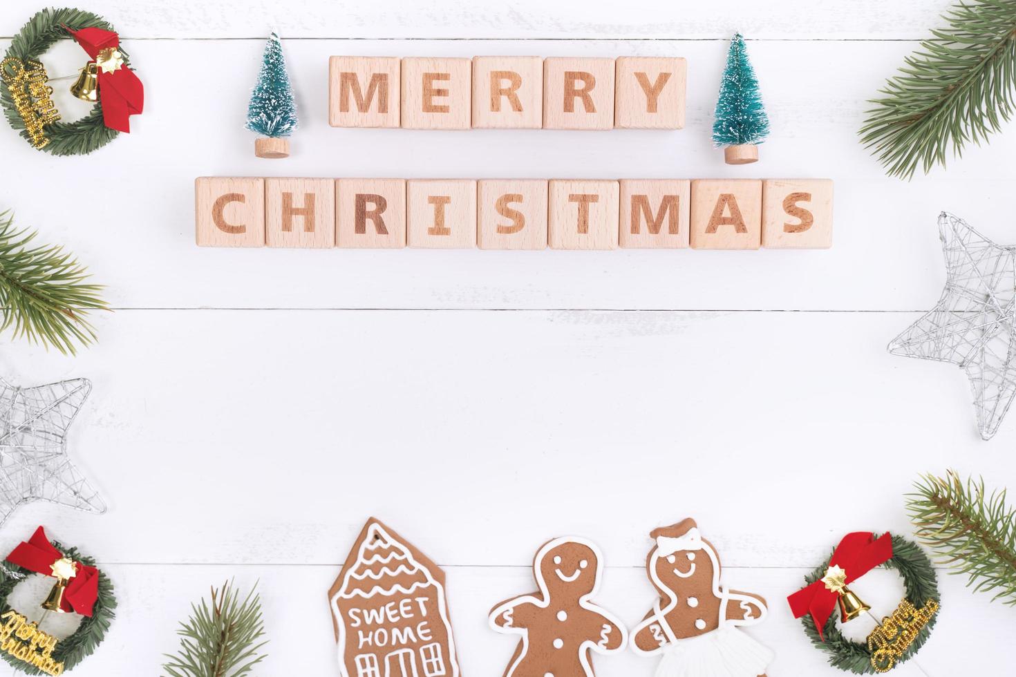 objetos de decoración de composición de concepto de navidad, corona de rama de abeto, galleta de hombre de pan de jengibre aislada en una mesa de madera blanca, vista superior, capa plana foto