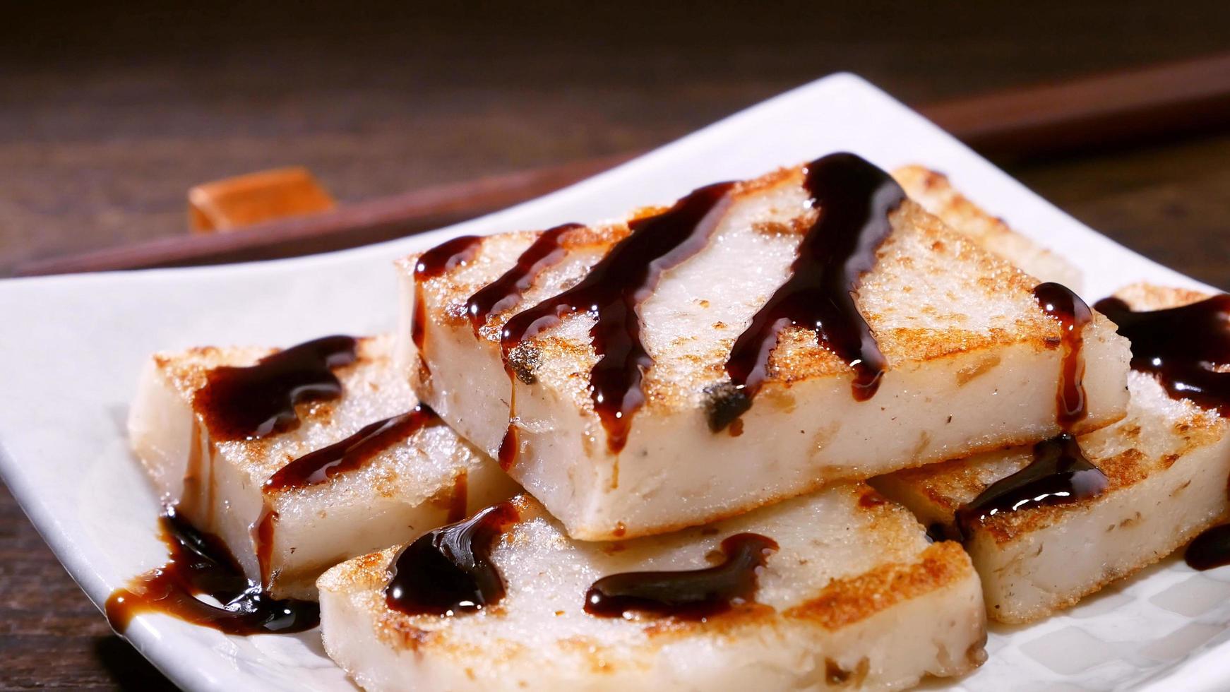 Pouring black soy sauce on ready-to-eat delicious turnip cake, Chinese traditional local dish radish cake in restaurant, close up, copy space. photo