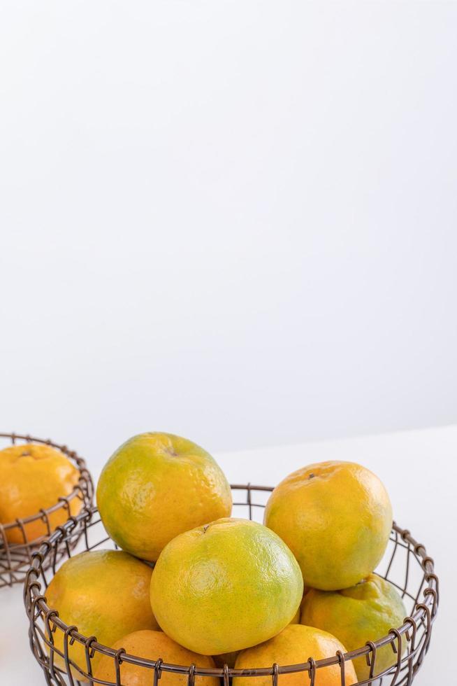 Beautiful peeled tangerines in a plate and metal basket isolated on bright white clean table in a modern contemporary kitchen island, close up. photo