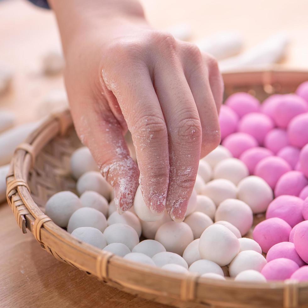 una mujer de asia está haciendo tang yuan, yuan xiao, albóndigas de arroz de comida tradicional china en rojo y blanco para el año nuevo lunar, festival de invierno, de cerca. foto