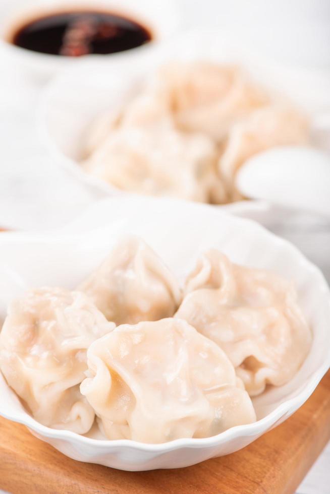 Fresh, delicious boiled pork gyoza dumplings, jiaozi on white background with soy sauce and chopsticks, close up, lifestyle. Homemade design concept. photo