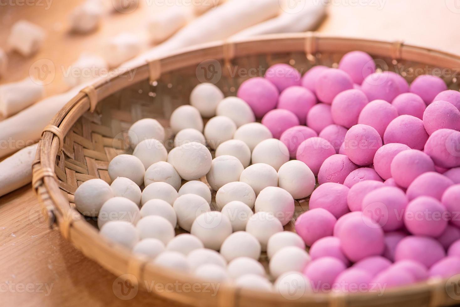 An Asia woman is making Tang yuan, yuan xiao, Chinese traditional food rice dumplings in red and white for lunar new year, winter festival, close up. photo