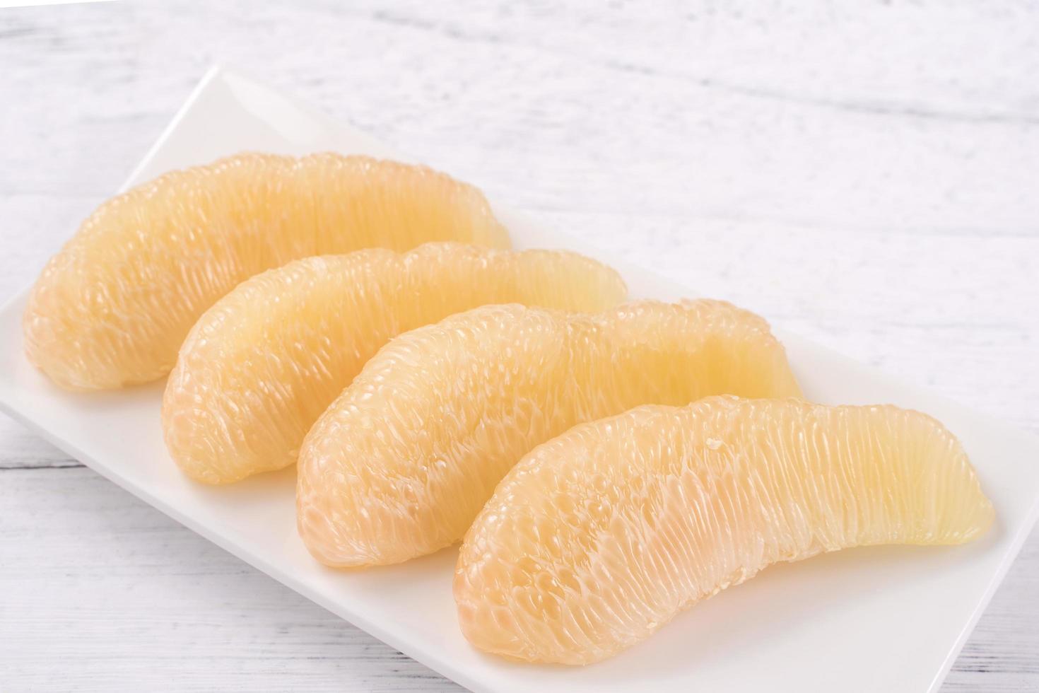 Fresh peeled pomelo, pummelo, grapefruit, shaddock on bright wooden table background. Seasonal fruit for Mid-Autumn Festival, close up, copy space. photo