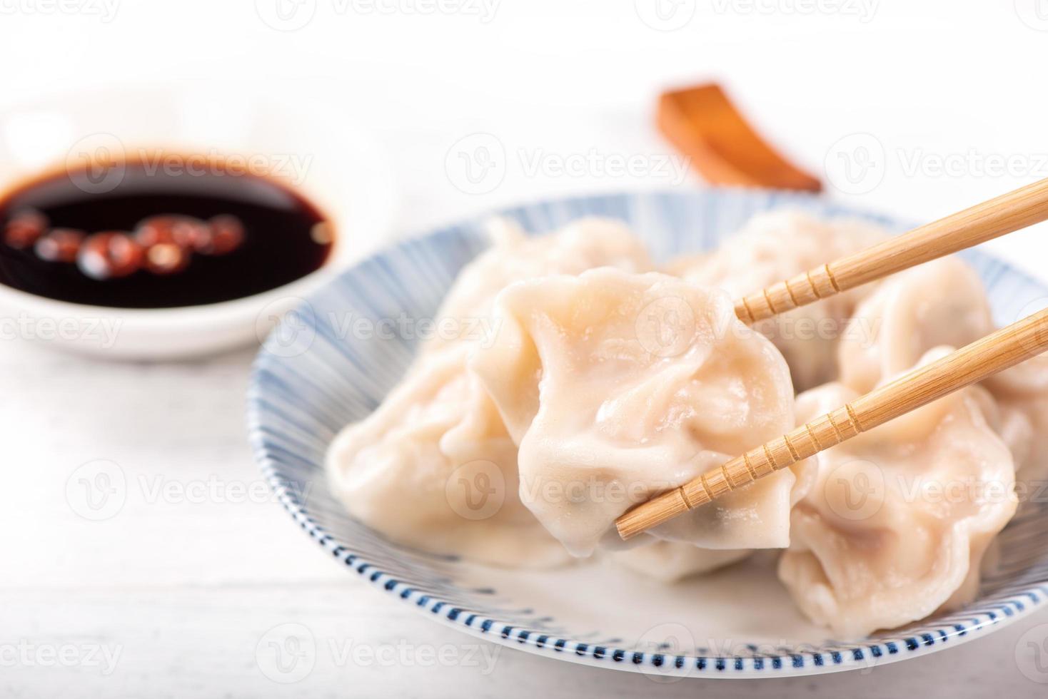 Fresh, delicious boiled pork, shrimp gyoza dumplings on white background with soy sauce and chopsticks, close up, lifestyle. Homemade design concept. photo