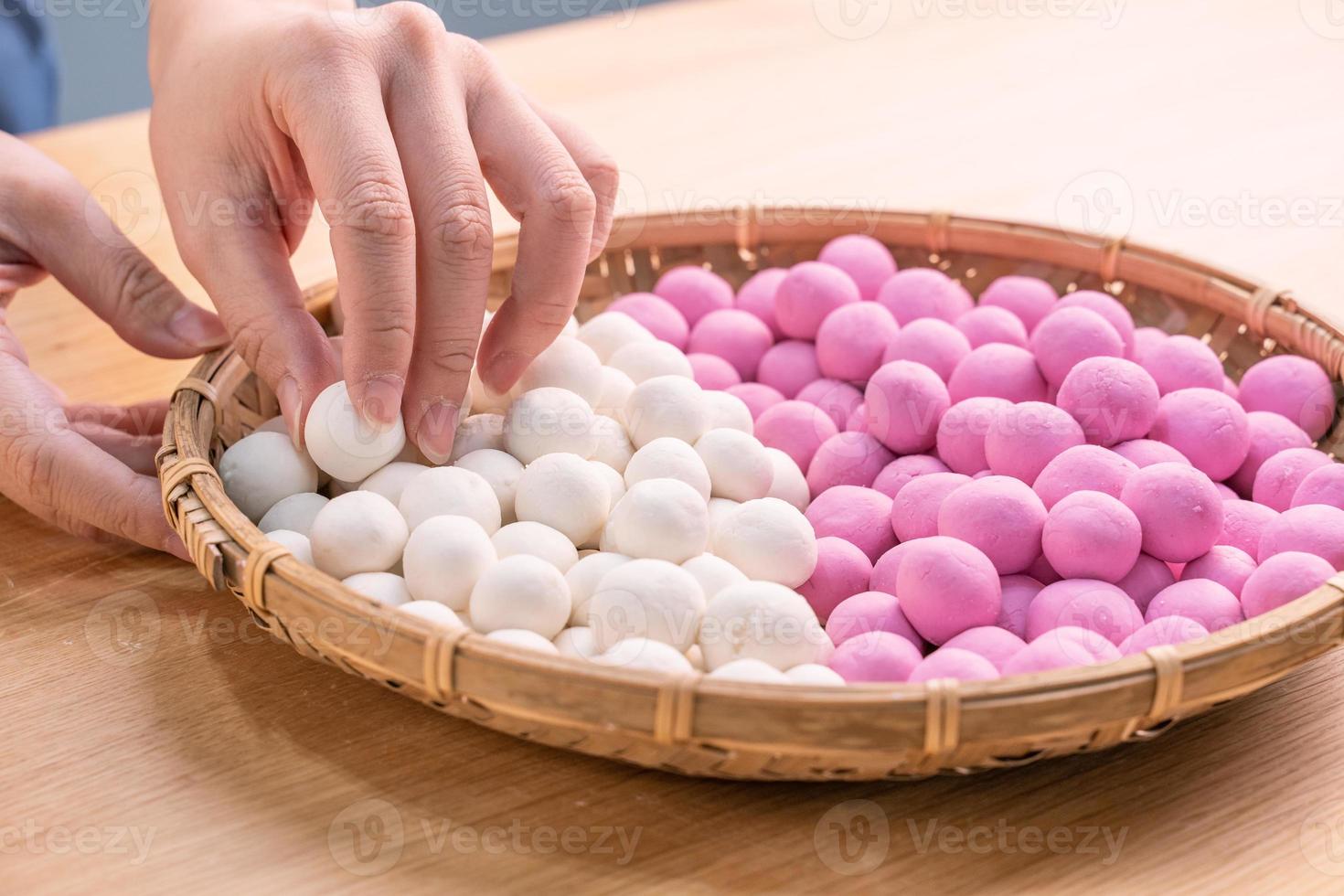 una mujer de asia está haciendo tang yuan, yuan xiao, albóndigas de arroz de comida tradicional china en rojo y blanco para el año nuevo lunar, festival de invierno, de cerca. foto