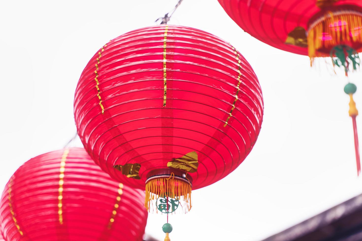 Beautiful round red lantern hanging on old traditional street, concept of Chinese lunar new year festival, close up. The undering word means blessing. photo