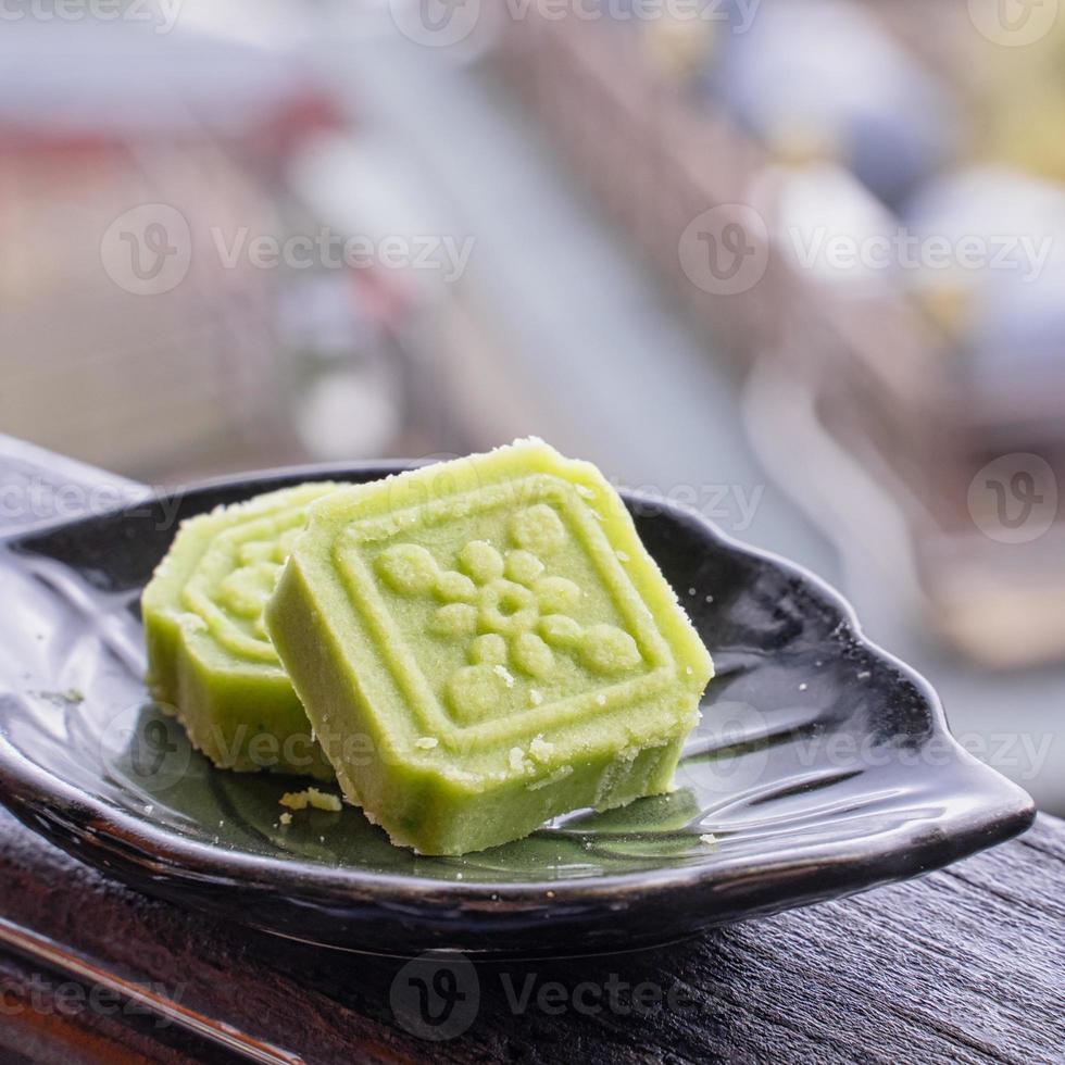 Delicious green mung bean cake with black tea plate on wooden railing of a teahouse in Taiwan with beautiful landscape in background, close up. photo