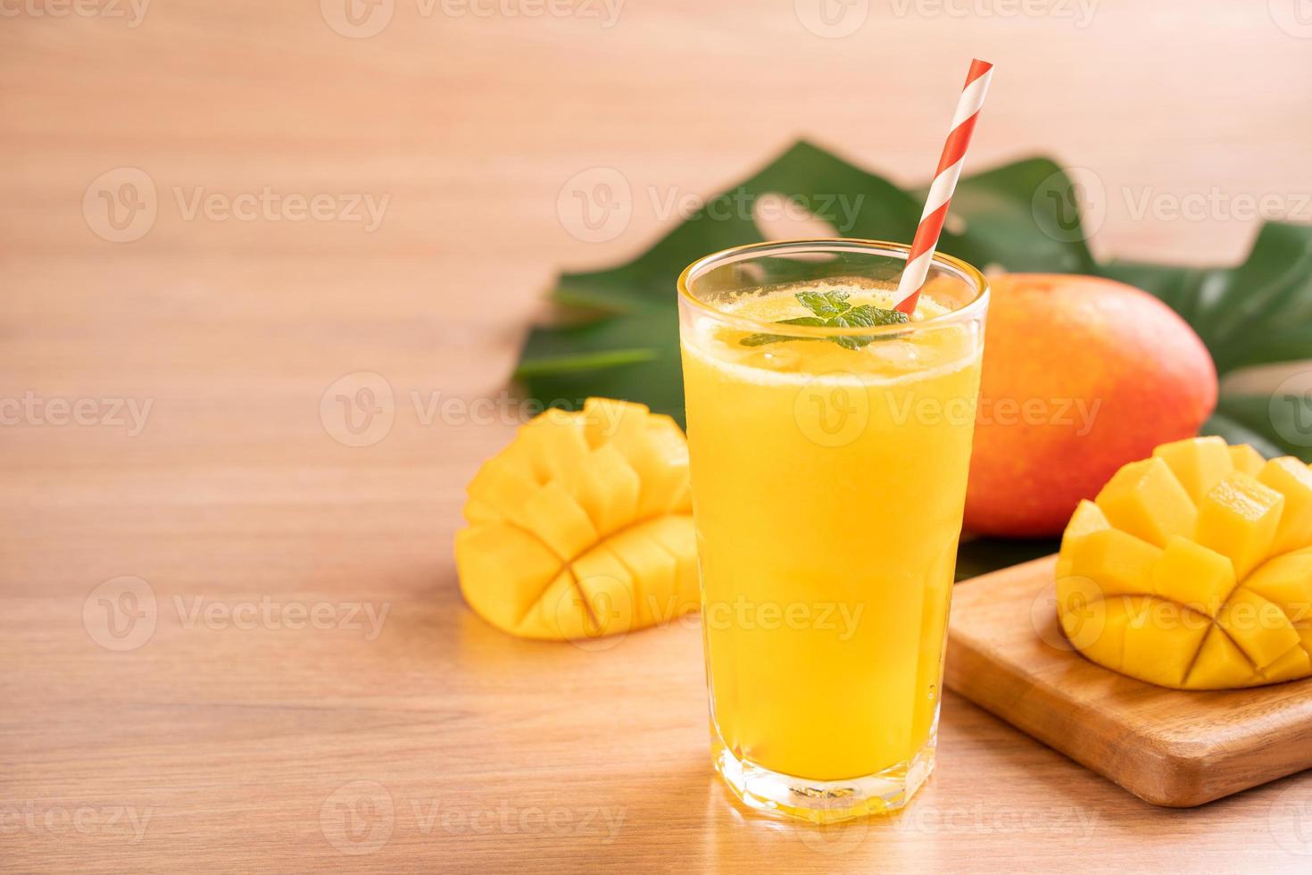 Fresh mango juice with beautiful chopped pulp flesh on bright wooden table background. Tropical fruit drink design concept. Close up, copy space. photo