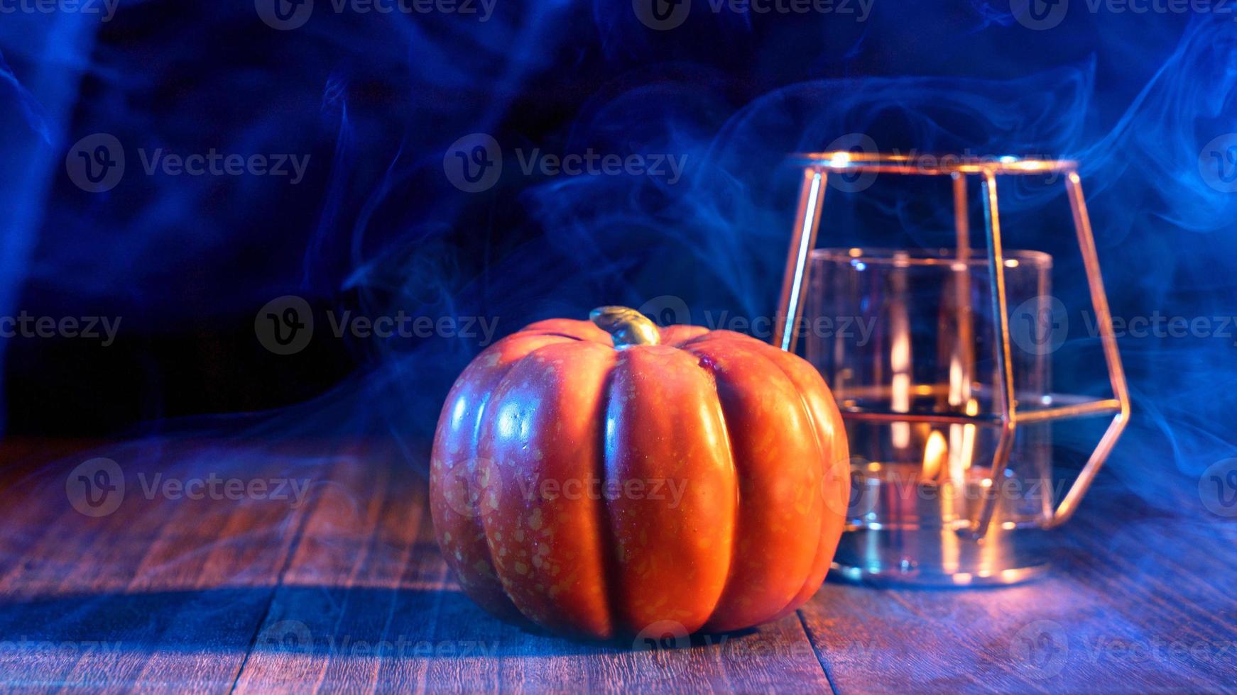 Halloween concept - Orange pumpkin lantern on a dark wooden table with double colored smoke around the background, trick or treat, close up. photo