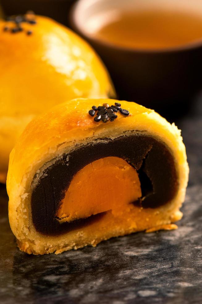 Tasty baked egg yolk pastry moon cake for Mid-Autumn Festival on black slate dark background. Chinese festive food concept, close up, copy space. photo